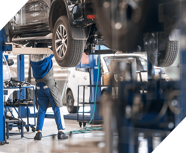 Mechanic inspecting car suspension detail and wheel car of lifted automobile at repair service station. Car service station. Preventive maintenance.